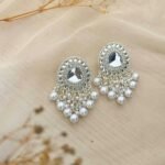 Beautiful silver earrings embellished with pearls on a soft fabric background.