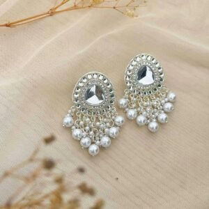 Beautiful silver earrings embellished with pearls on a soft fabric background.