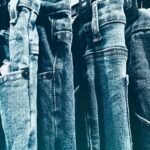 A collection of blue denim jeans hanging closely on a rack in a retail store.